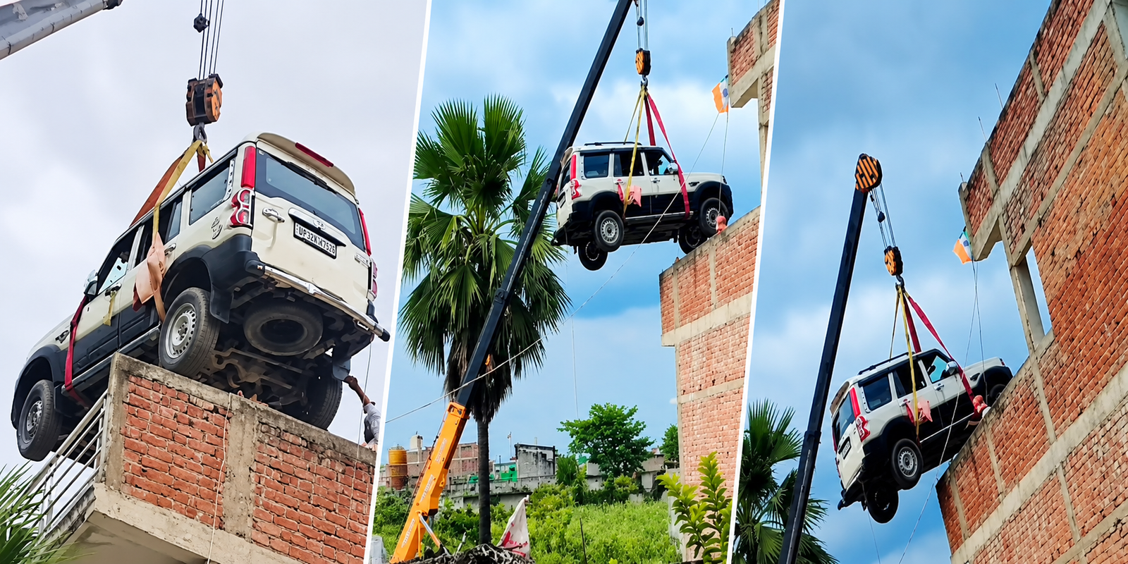 A crane lifts a Mahindra Scorpio onto a house rooftop.