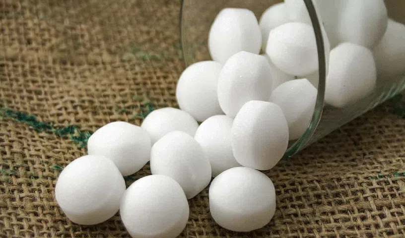 Naphthalene balls stored in a cupboard with clothing and household items.