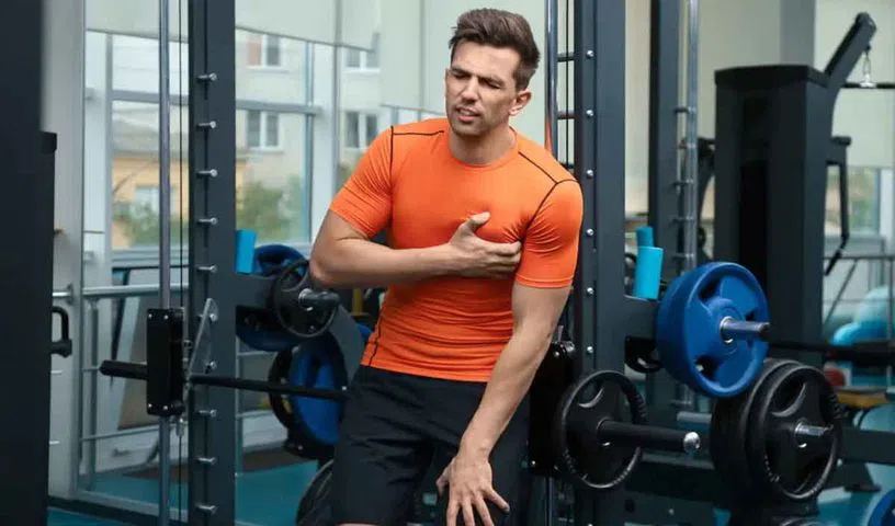 Protein supplement powder and shaker bottle beside gym workout equipment.