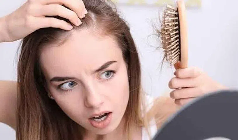 Woman noticing excessive hair fall while combing her hair.