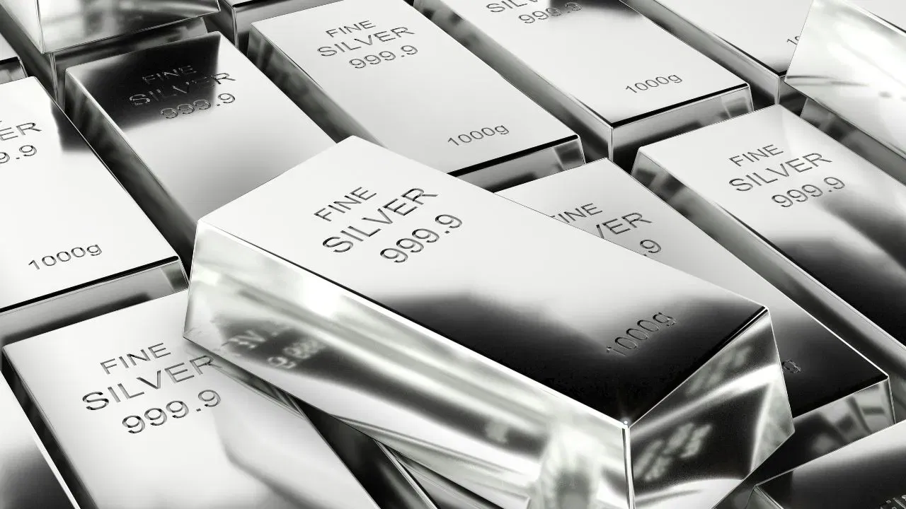 Silver bars and coins representing falling silver prices in the market.
